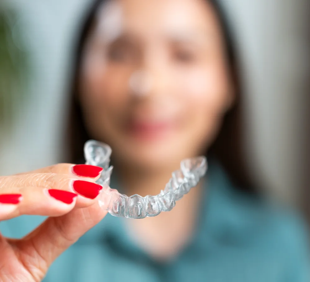A woman holding a clear aligner