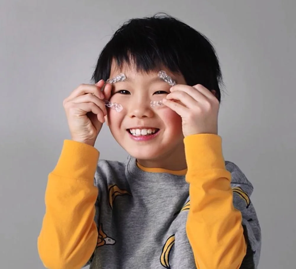 A child holding up a clear aligner