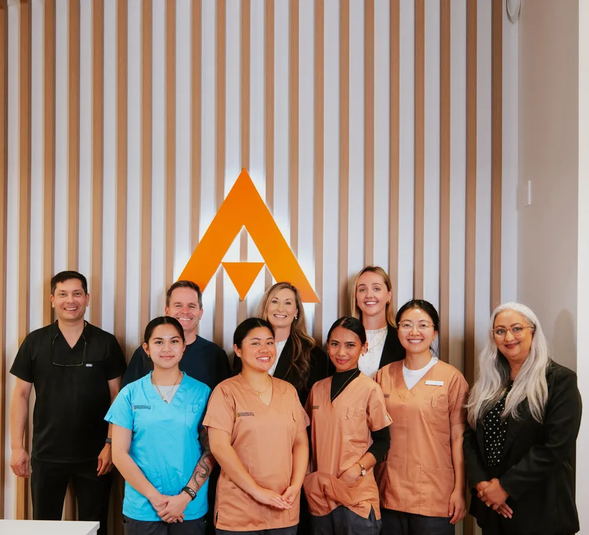The Auckland City Orthodontics team in front of the practice logo