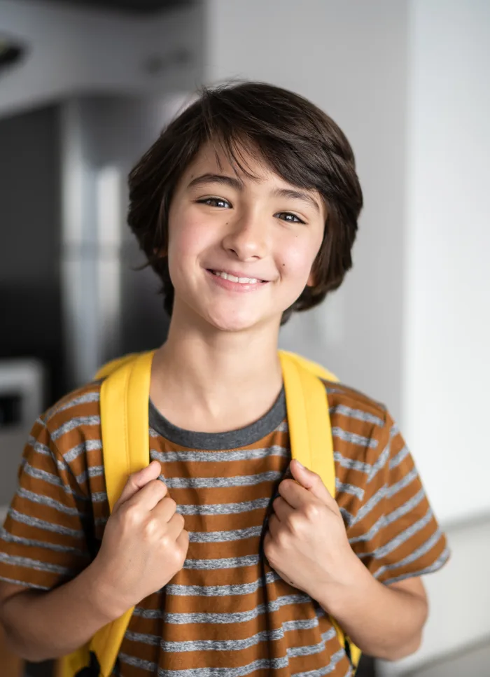A smiling school-age child with a backpack