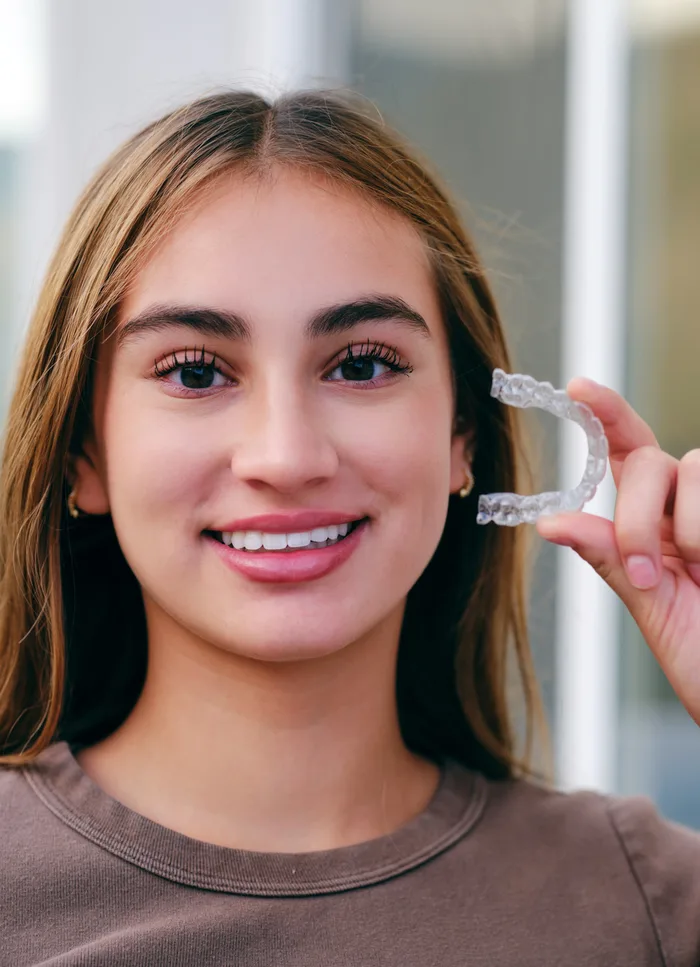 A teenager holding a clear aligner